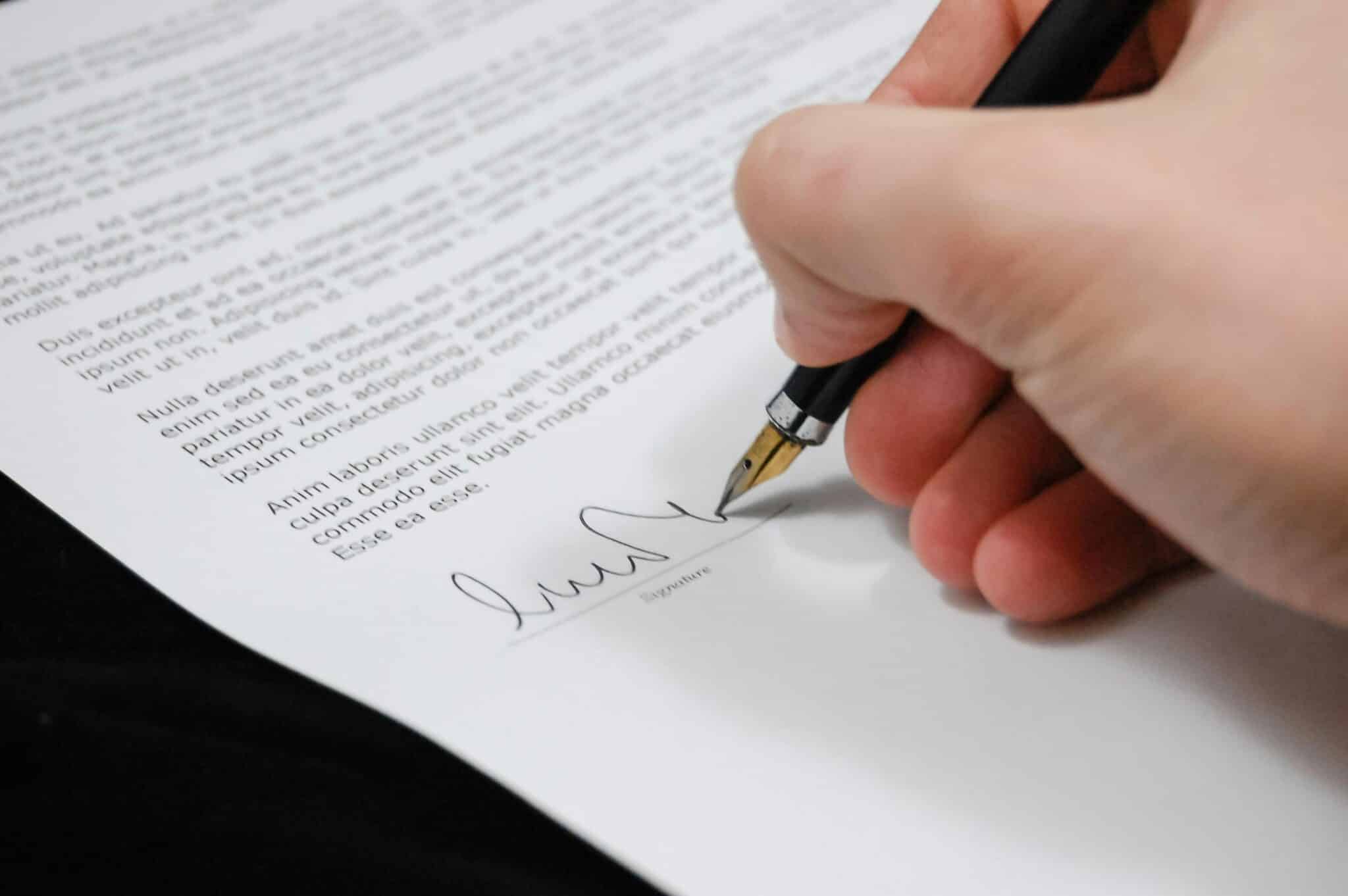 Une main signe élégamment un document soigné.