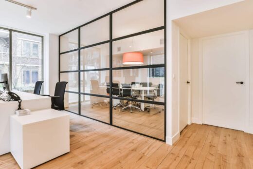 Bureau moderne avec cloisons vitrées, bureaux, chaises. Grandes fenêtres laissant passer la lumière naturelle, idéal pour commerce.